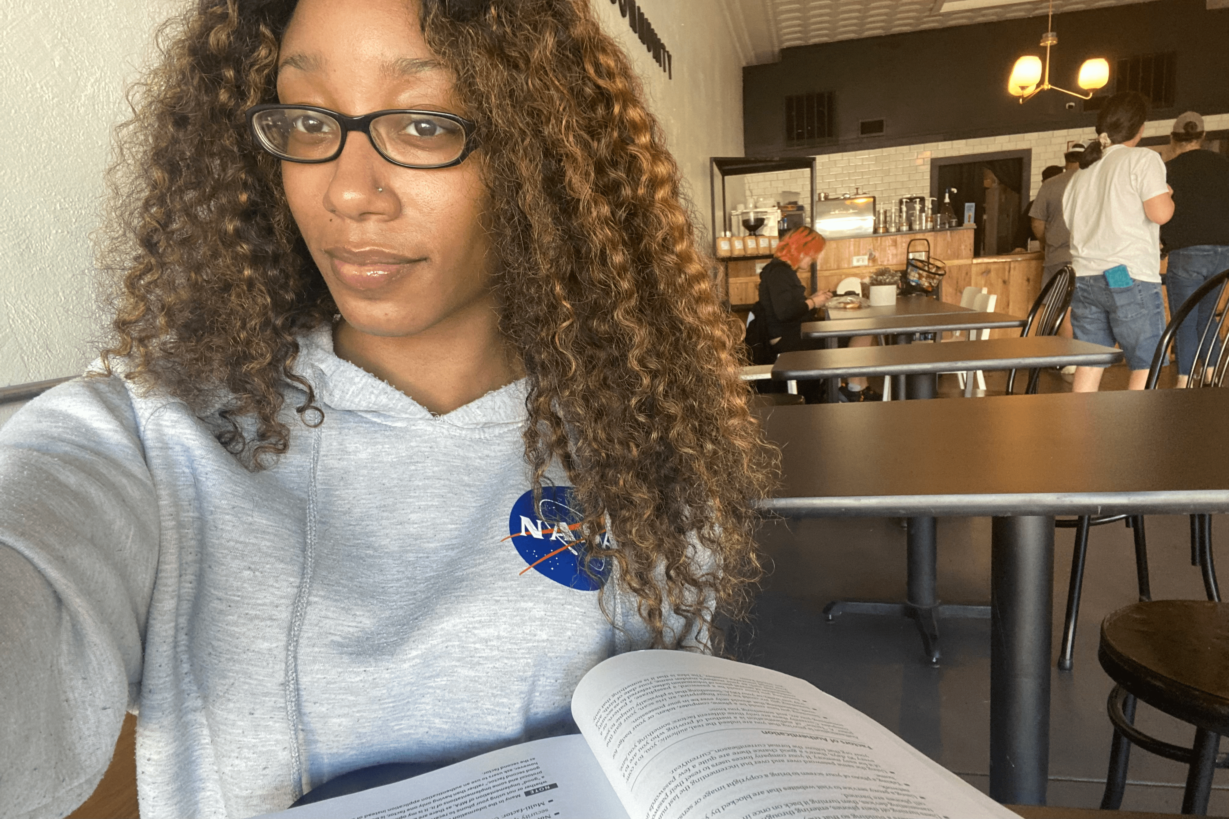 Tae'lur Alexis in a coffeeshop reading a book